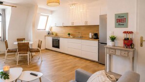 A modern kitchen with white cabinets, a wooden countertop, and a hanging light fixture.
