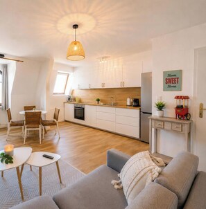 Une cuisine moderne avec des armoires blanches, un plan de travail en bois et un luminaire suspendu.