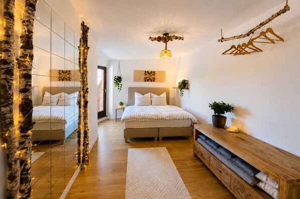 Une chambre avec deux lits, un miroir, une commode en bois et une plante suspendue.