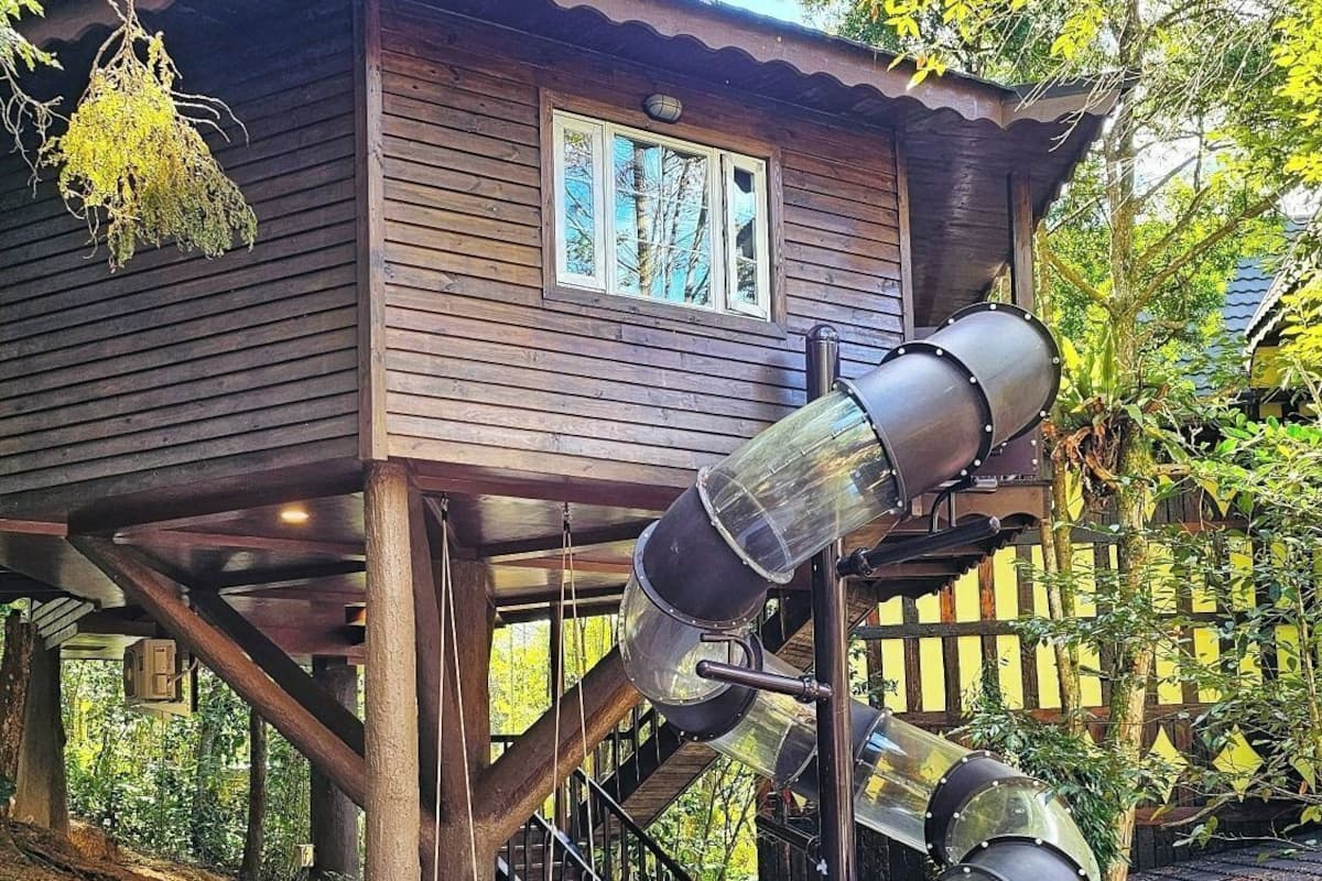 A wooden cabin with a slide extending from its roof.