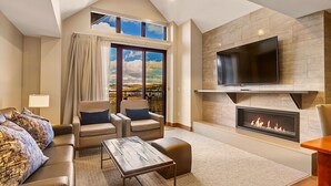 Una sala de estar moderna con chimenea, televisor de pantalla plana y un ventanal con vistas panorámicas.