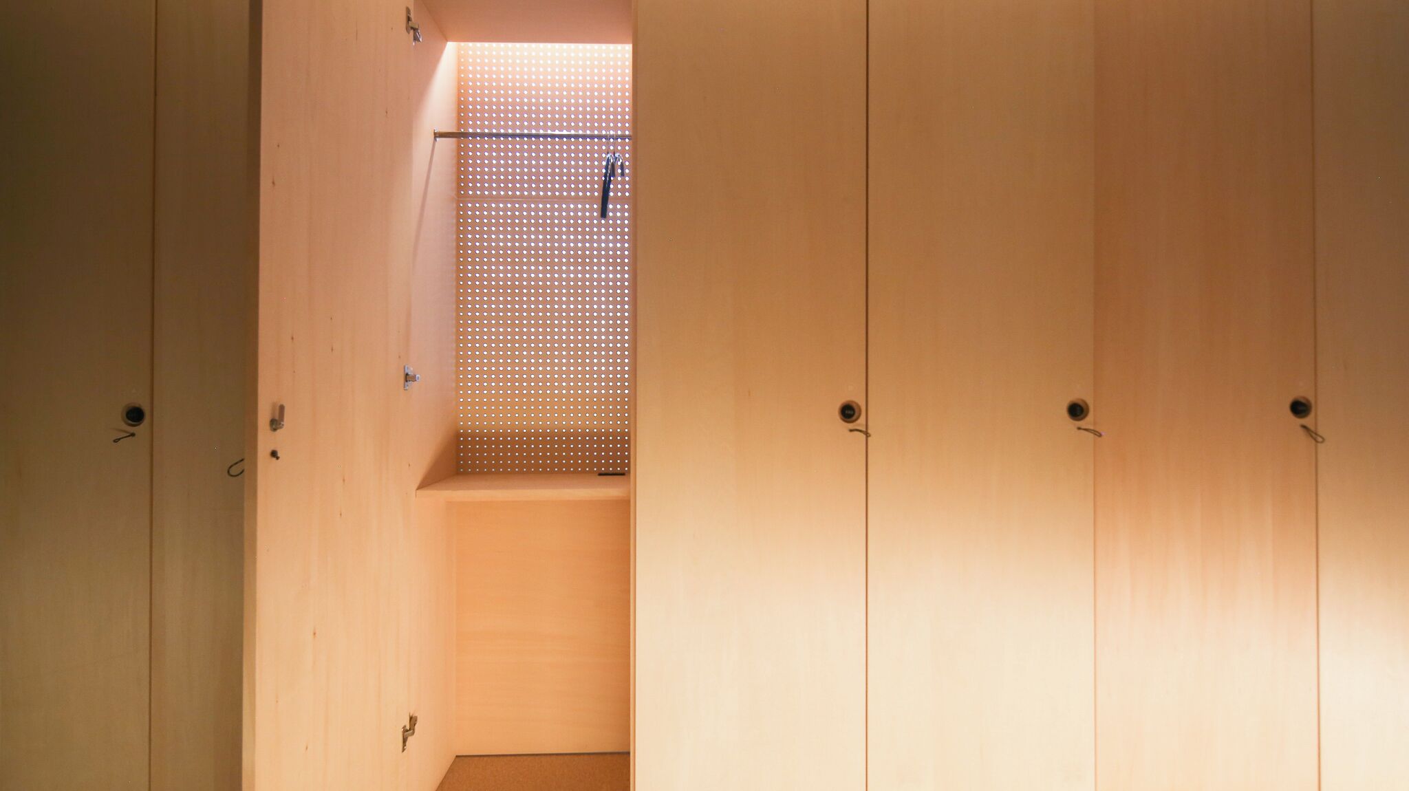 A wooden interior with a sloped ceiling and a perforated panel.