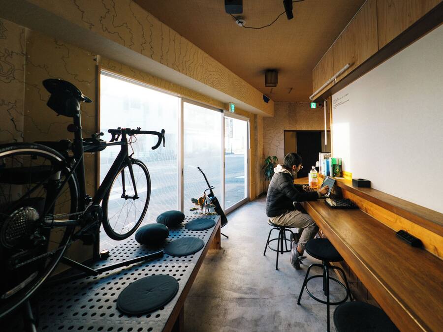 Una stanza con una bicicletta, un tavolo con degli sgabelli, una lavagna a fogli mobili e una vista panoramica attraverso ampie finestre.