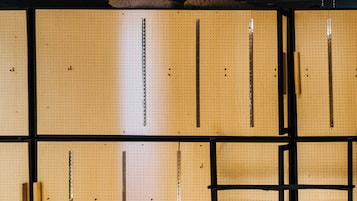 A pegboard wall with various tools and metal rods.
