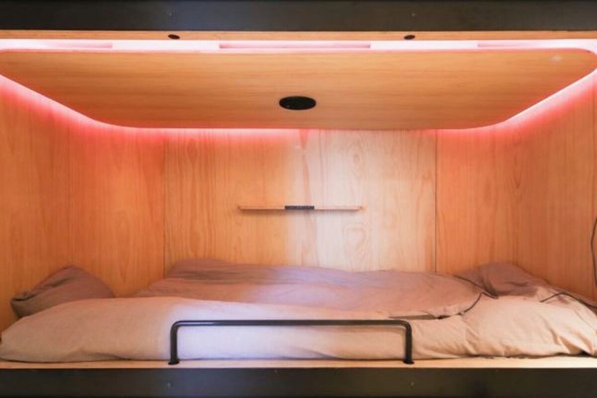 Um quarto pequeno e acolhedor, com cama, um nicho e iluminação no teto.