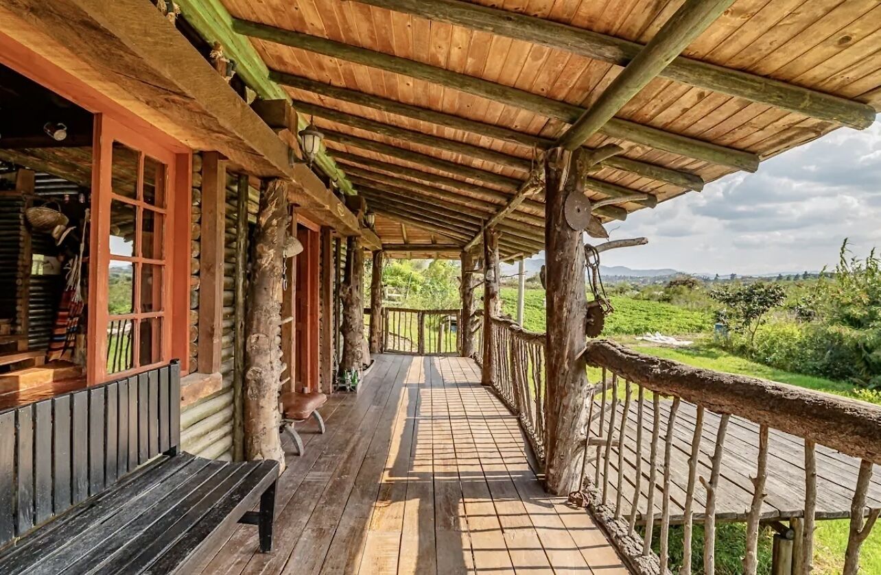 A wooden porch with a view of a green landscape.