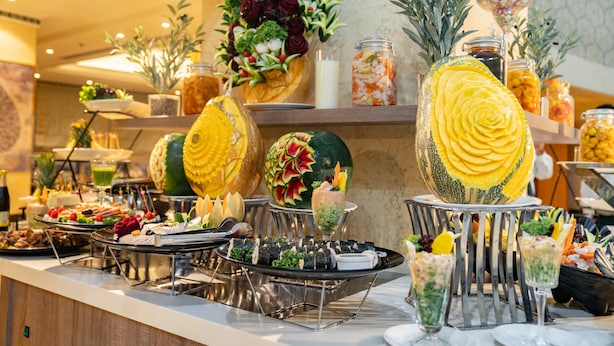 Un buffet con diversi piatti, tra cui sushi, frutta e un elemento decorativo al centro.