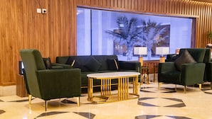 Una hall con un divano verde, un tavolino da caffè dorato e un pavimento decorato.