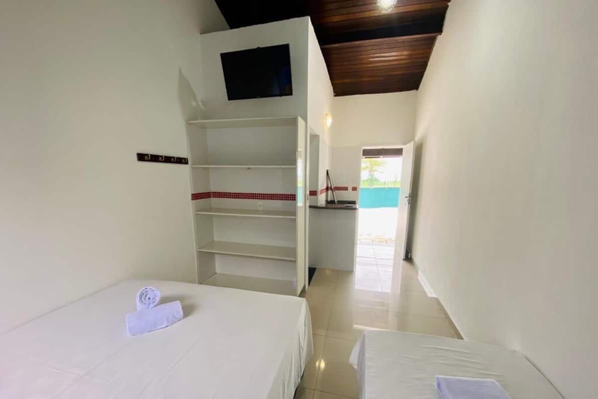 A hotel room with two beds, a TV on the wall, and a view of the outside.