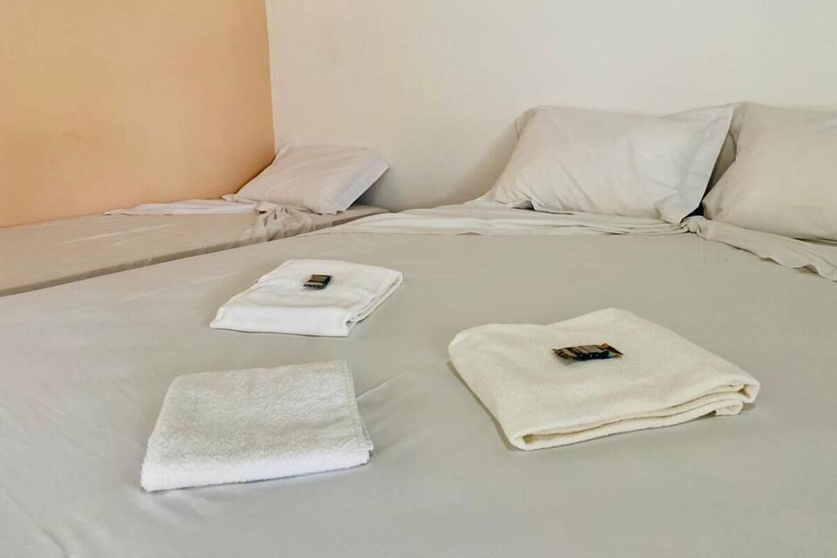 A neatly made bed with two pillows and two folded towels.