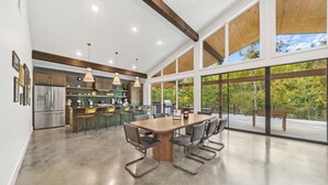 Une cuisine spacieuse dotée d’un grand îlot central, d’appareils électroménagers modernes et de grandes fenêtres offrant une vue sur l’extérieur.