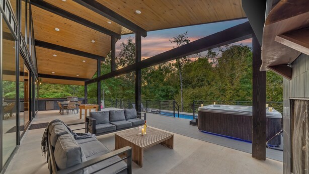 Une vaste terrasse extérieure dotée d’un plafond en bois, d’un canapé, d’une table basse et d’un jacuzzi.