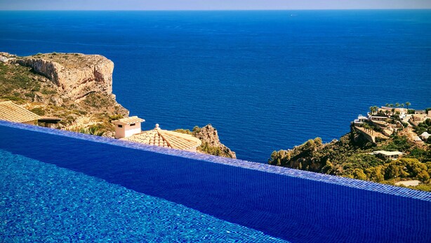 Un hotel frente al mar con piscina, acantilados rocosos y arquitectura tradicional.