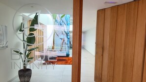 Un interior moderno con una puerta de madera, una planta en maceta y vistas a un balcón con barandilla.
