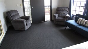 A room with two grey armchairs, a blue sofa, and a dark carpet. - Hooked on Hardwicke - Short walk to the beach!  Off Peak special! (Hardwicke Bay)