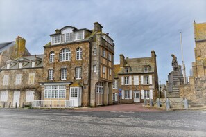 A historic stone building with multiple windows and a statue in front. - House "henri Chardon" , A travel on the sea ! (Barfleur)