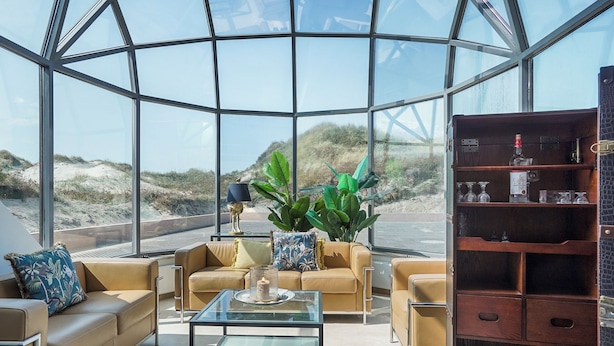 A modern interior with a glass dome, beige sofas, a glass coffee table, and a wooden wine rack. - One of Denmarks Most Famous Architect Spa Houses, First Beach Line (Blokhus)