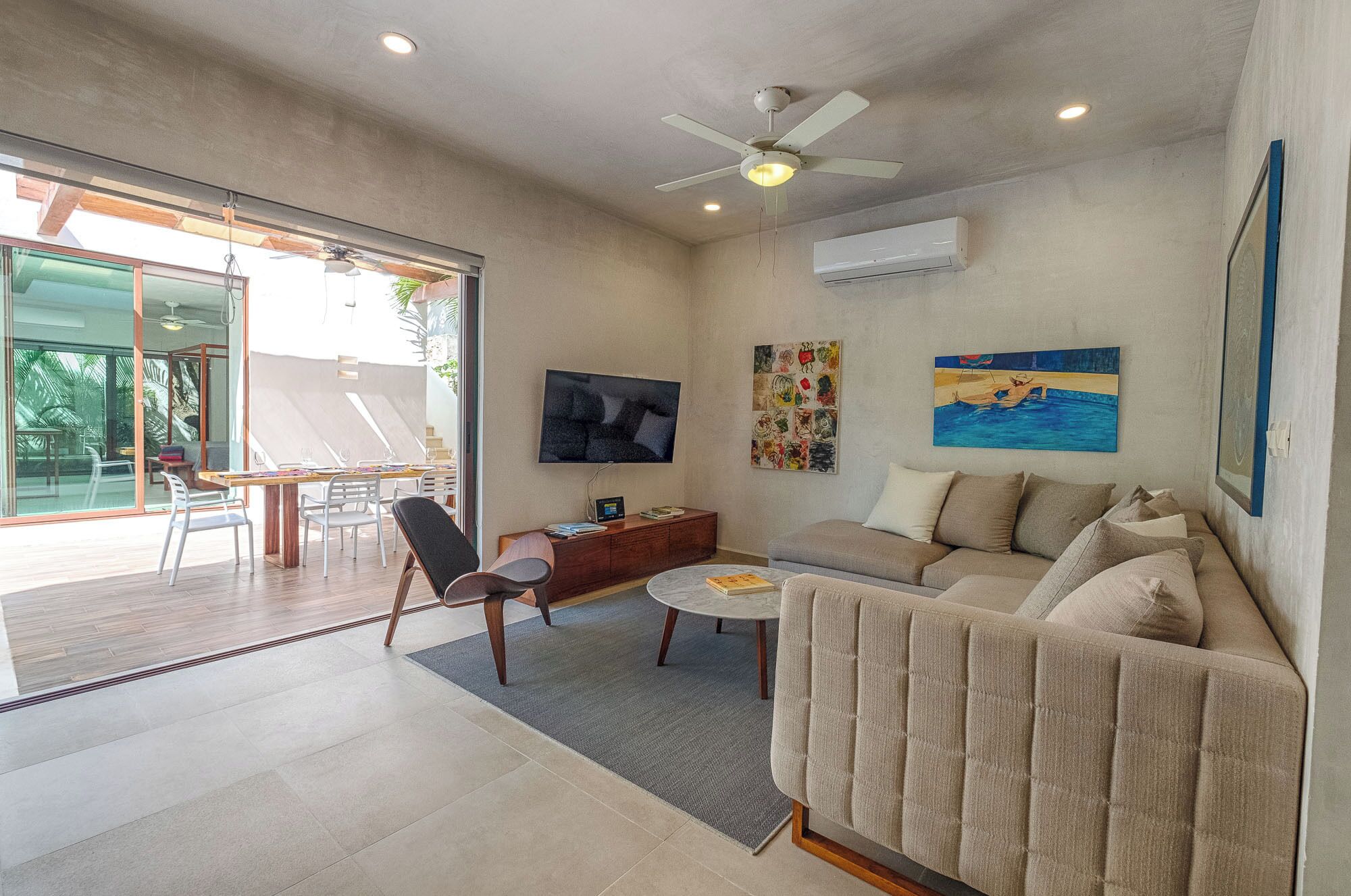 A modern living room with a sofa, a coffee table, a TV, and artwork on the walls.