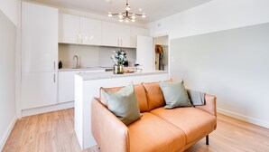 A modern kitchen with white cabinetry, a central island, and a pendant light. - Urban Oasis by Keystone (Newport)