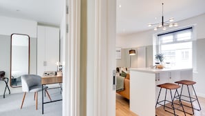 A modern kitchen with a central island, bar stools, and a large window providing natural light. - Urban Oasis by Keystone (Newport)