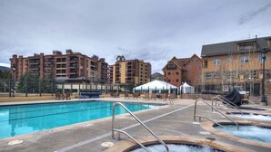 A swimming pool with hot tubs, lounge chairs, and a tent.