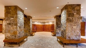 A lobby with stone pillars, wooden benches, and a stone floor.