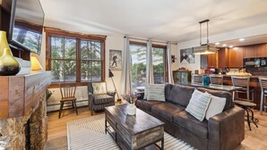 A spacious living room with a fireplace, a dining area, and a kitchen.