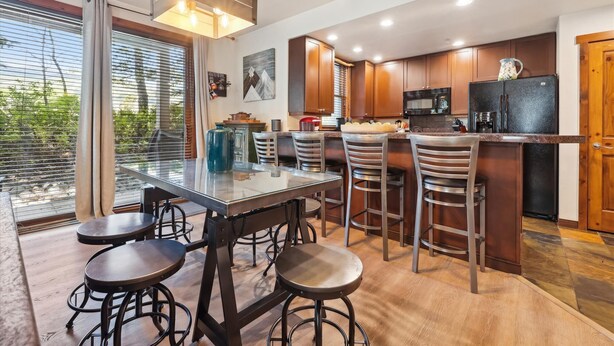 A modern kitchen with a central island, bar stools, and wooden cabinets.