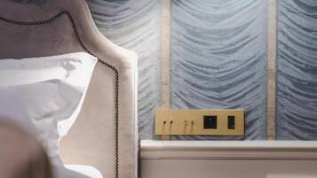 Habitación de hotel con cama, lámpara de noche, mesita de noche y pared con textura.