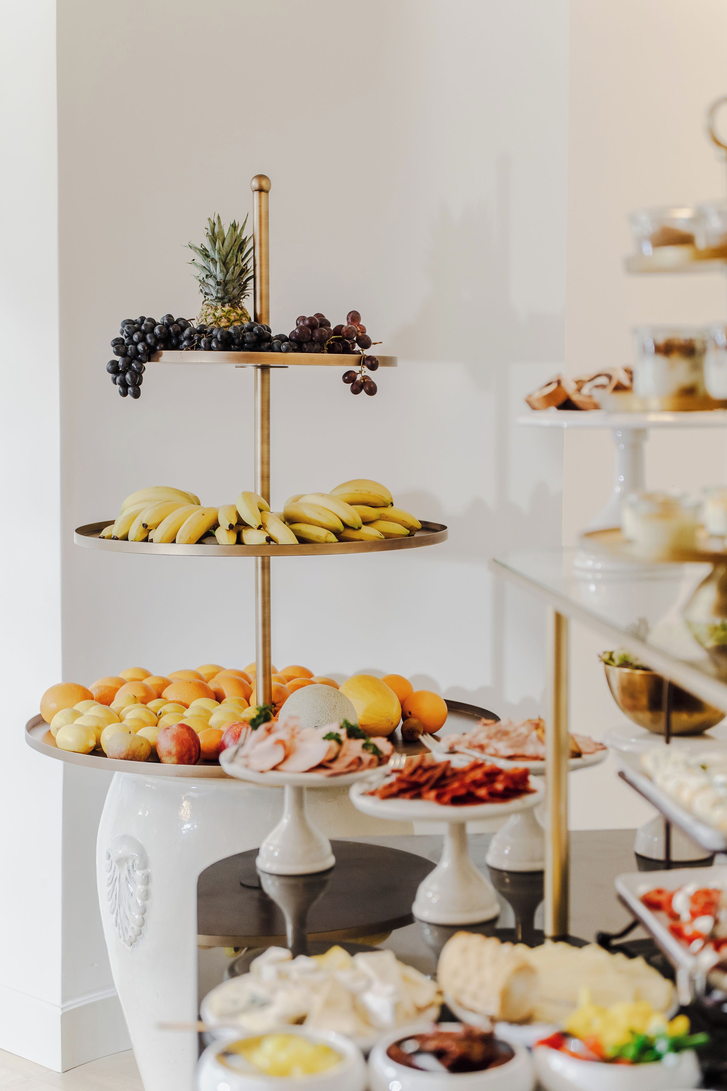 A multi-tiered fruit and dessert display with various fruits and pastries.