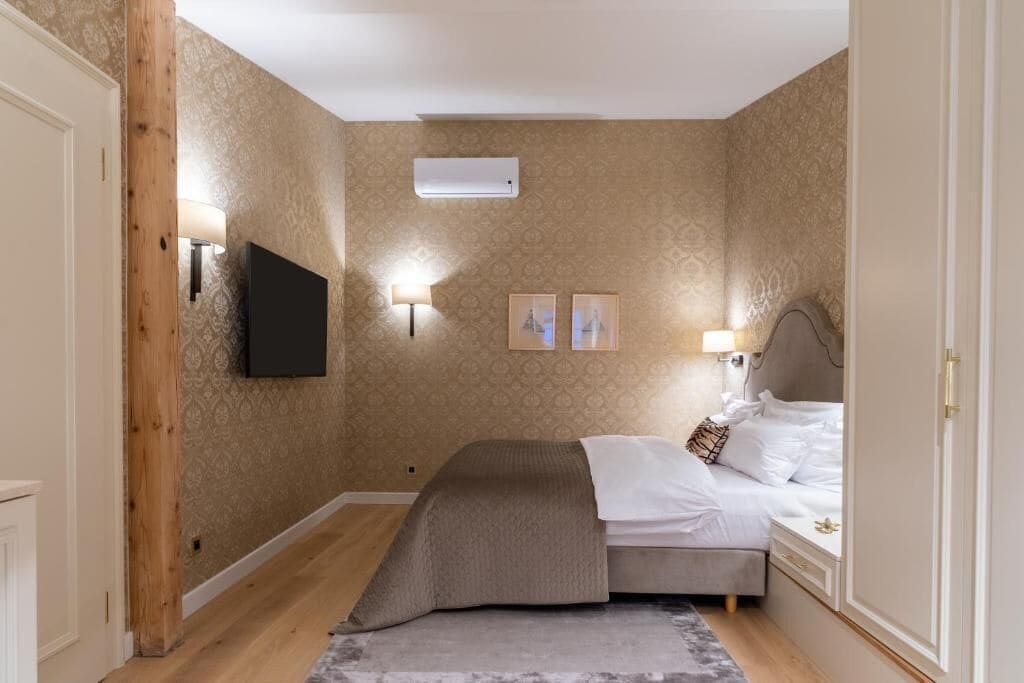 Een slaapkamer met een bed, een tv aan de muur en twee wandlampen.