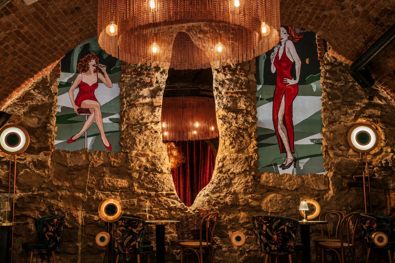 Un teatro con fachada de piedra, cortinas rojas y un candelabro.