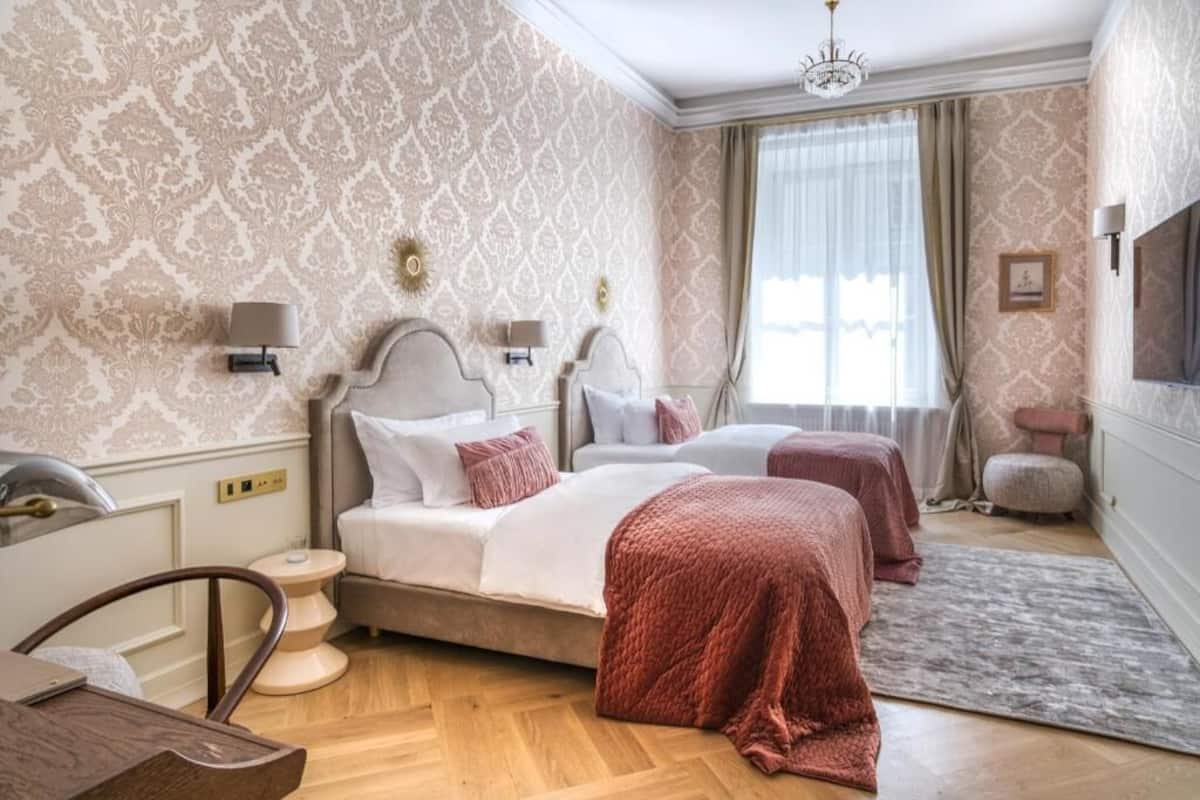 A hotel room with two beds, a desk, and a chair.
