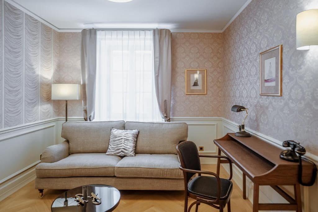 A living room with a sofa, a coffee table, a desk with a lamp, and a chair.