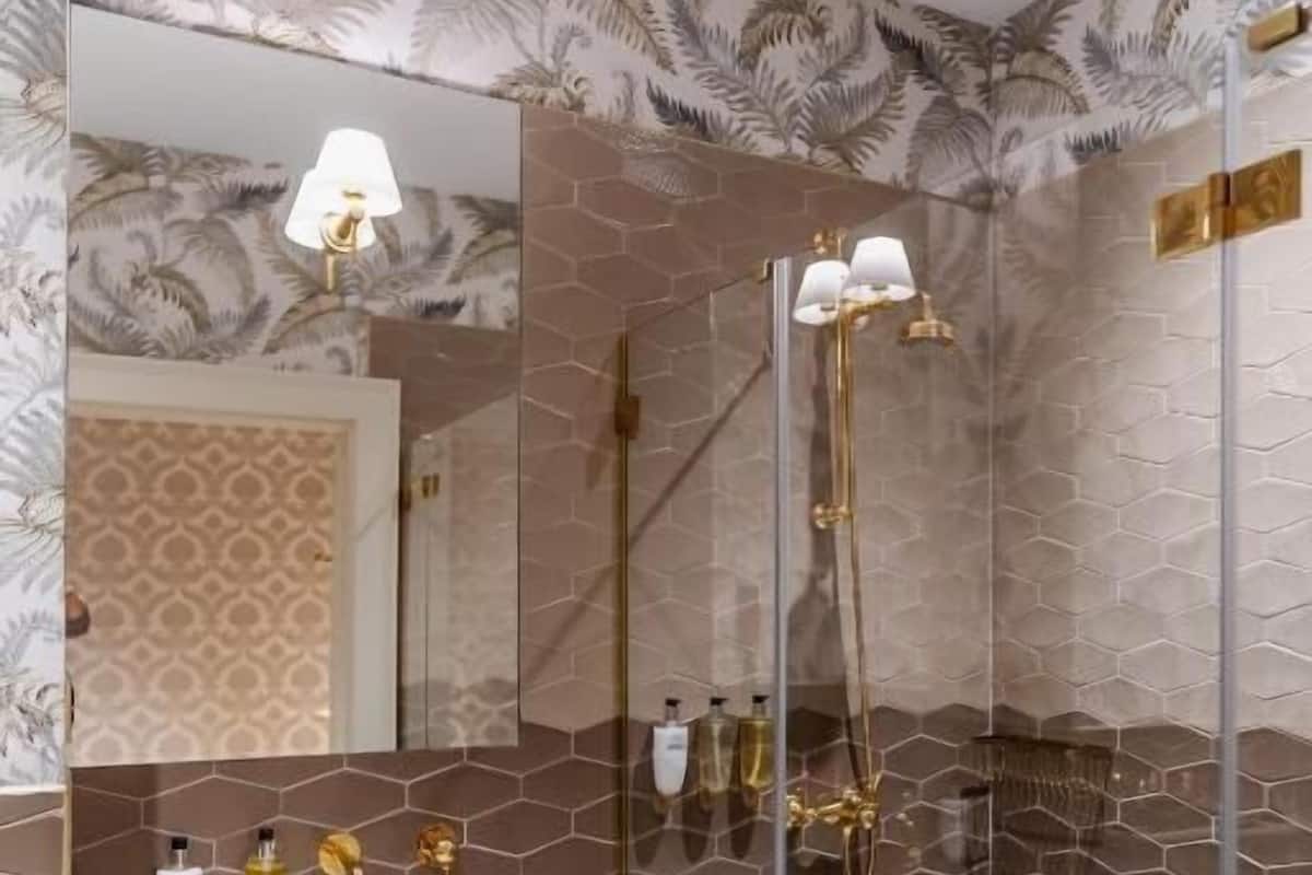 A modern bathroom with a glass-enclosed shower, a white marble sink, and gold fixtures.