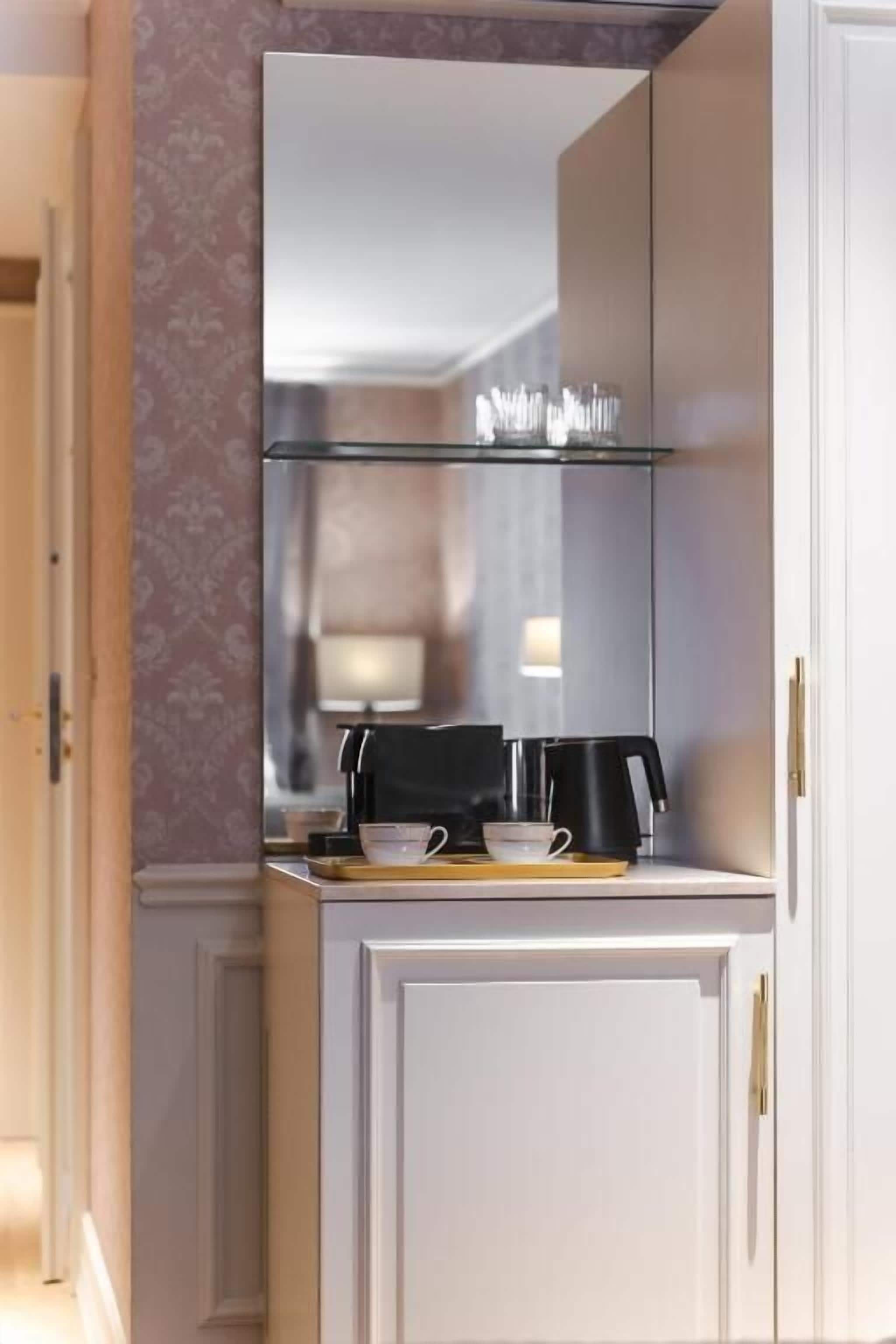 A modern kitchen with a built-in microwave, a coffee maker, and a tea set on the counter.
