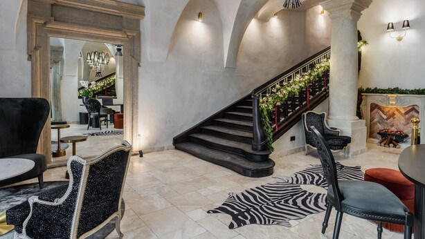 Un amplio vestíbulo con escalera, elegantes sillas y chimenea.