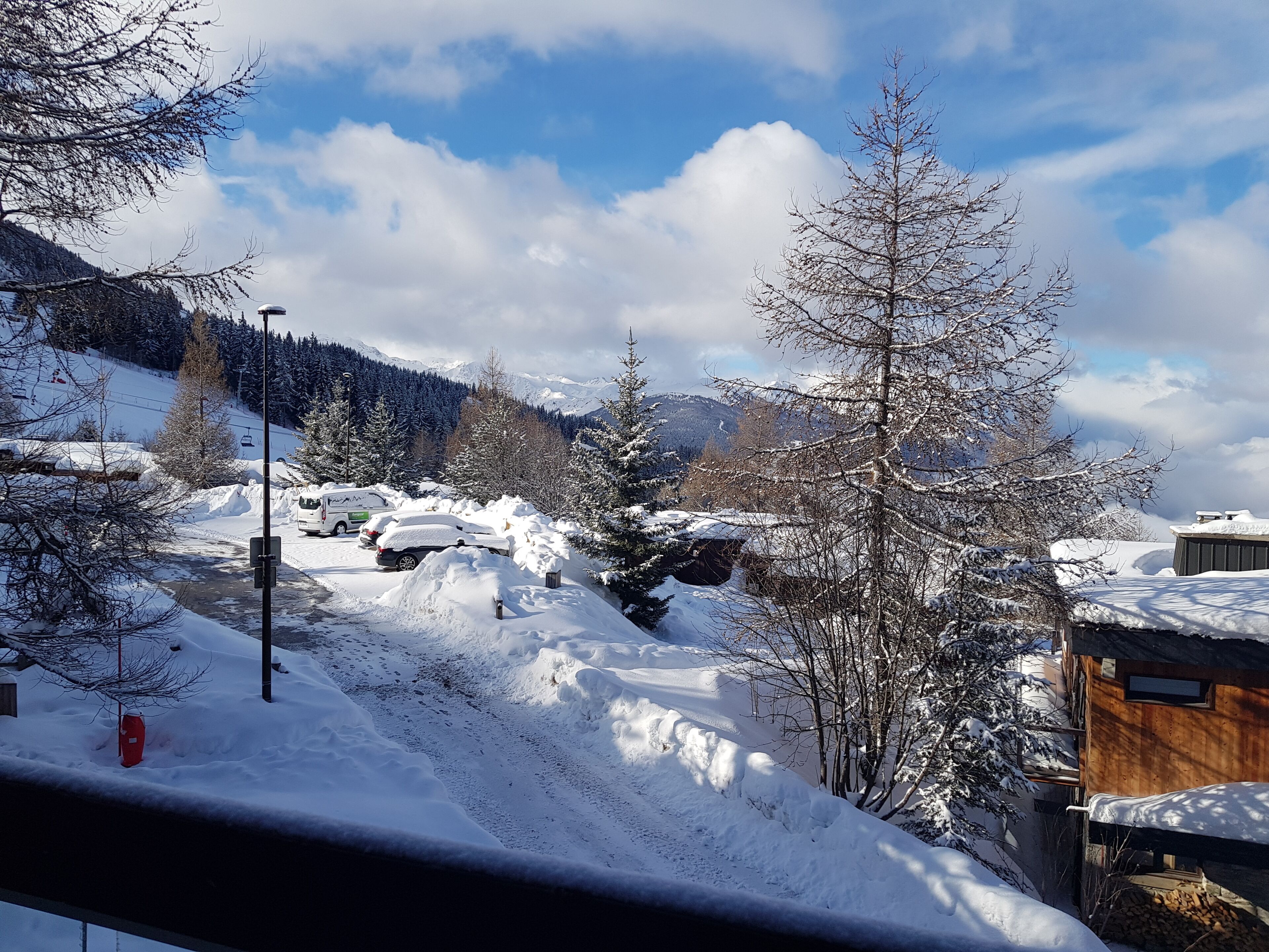 Schneelandschaft mit einer Hütte, einer Straße und einem Berg im Hintergrund.
