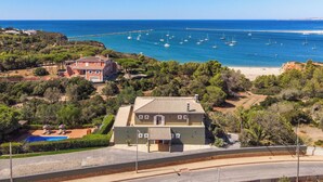 Um imóvel costeiro com uma casa grande, piscina e vista para o mar com barcos.