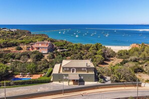 A coastal property with a large house, a swimming pool, and a view of the sea with boats.