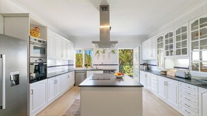 Uma cozinha moderna com armários brancos, eletrodomésticos de aço inoxidável e uma ilha central.