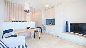 A modern kitchen with white cabinets, a wooden dining table, and a blue vase. - Hedera Estate, Hedera Studio 1 (Dubrovnik)