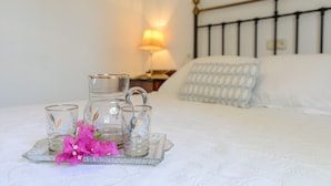 A neatly made bed with a metal headboard, a bedside table with a lamp, and a tray with glassware and flowers on the bed. - Casa Rural Andaluza, Rodeada de Vegetación, Piscina. Ideal Vacaciones en Familia (Alhaurín de la Torre)