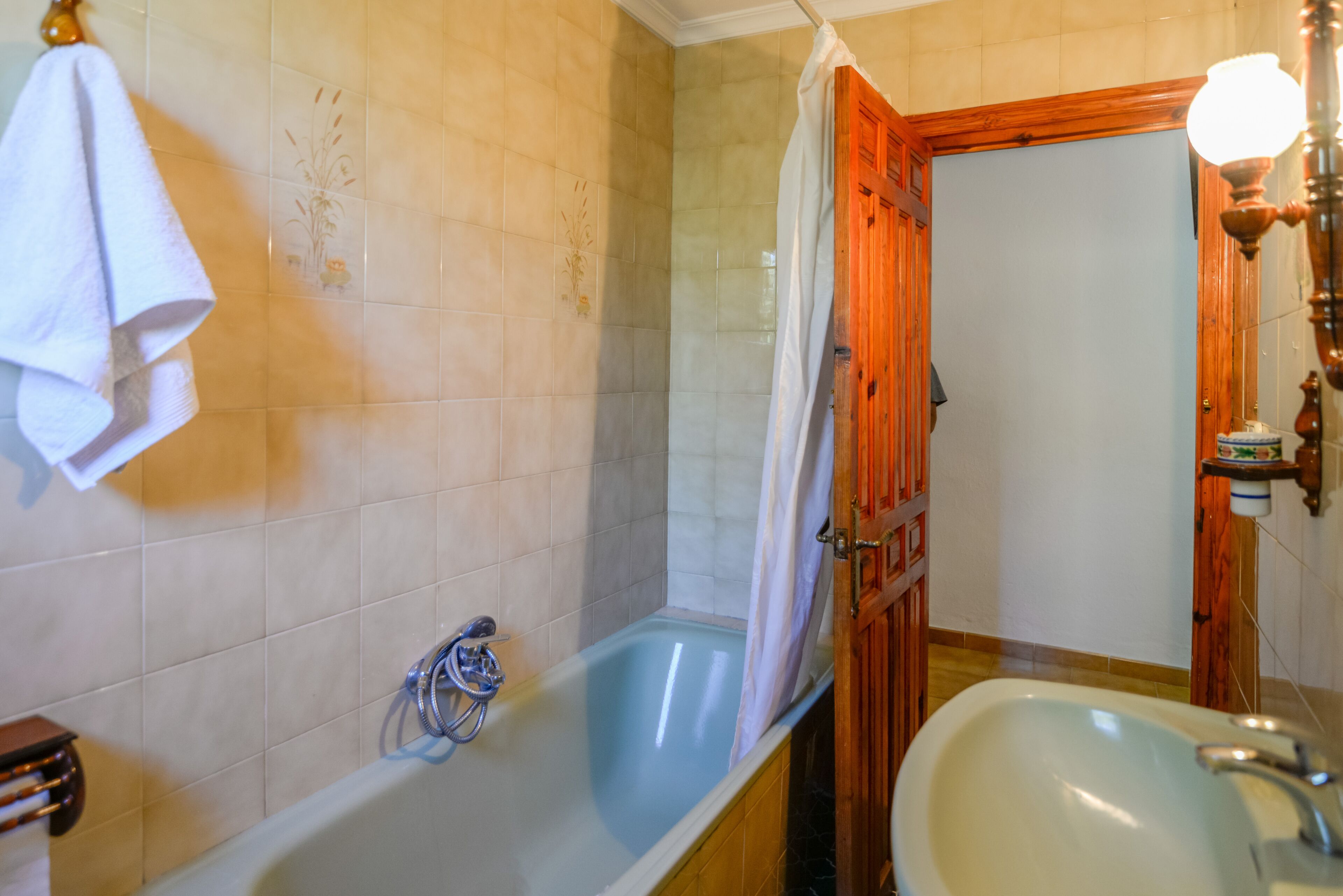 A bathroom with a bathtub, a sink, and a wooden door.