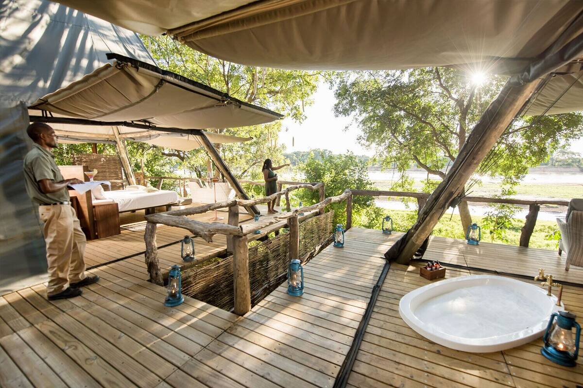 A wooden deck with a pool, lounge chairs, and a view of a body of water.