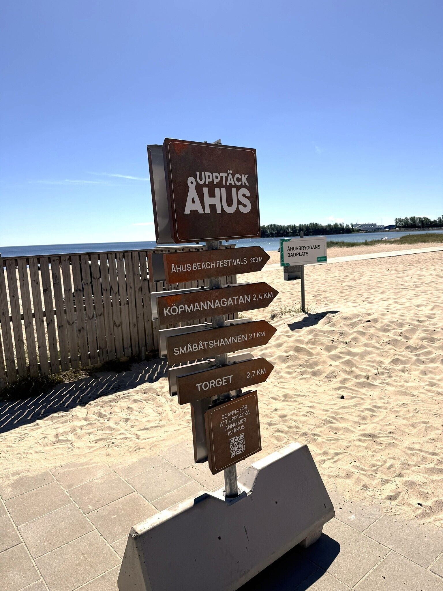 A directional signpost at a beach with multiple arrows pointing to various attractions.