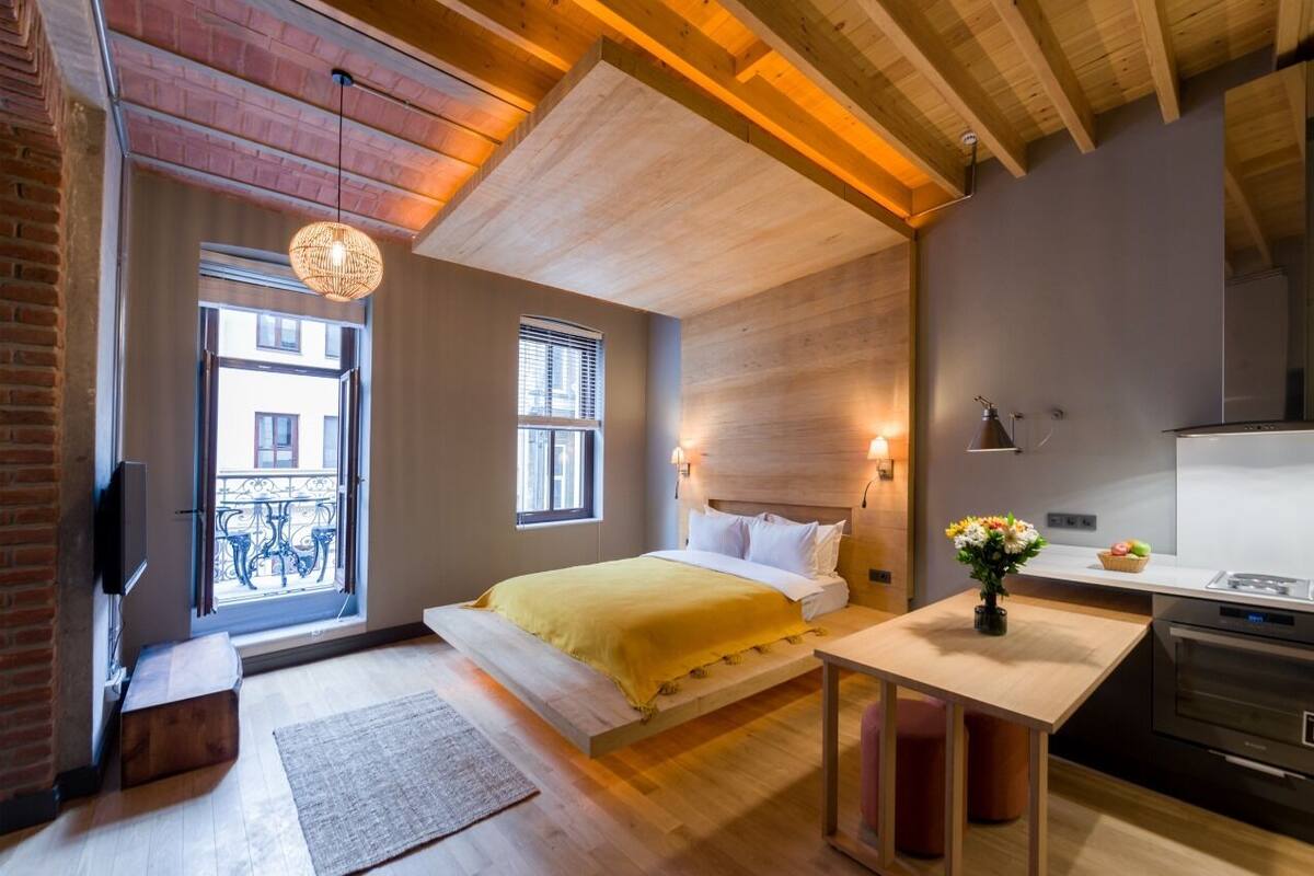 A modern bedroom with a bed, bedside table, and a view of the outside balcony.