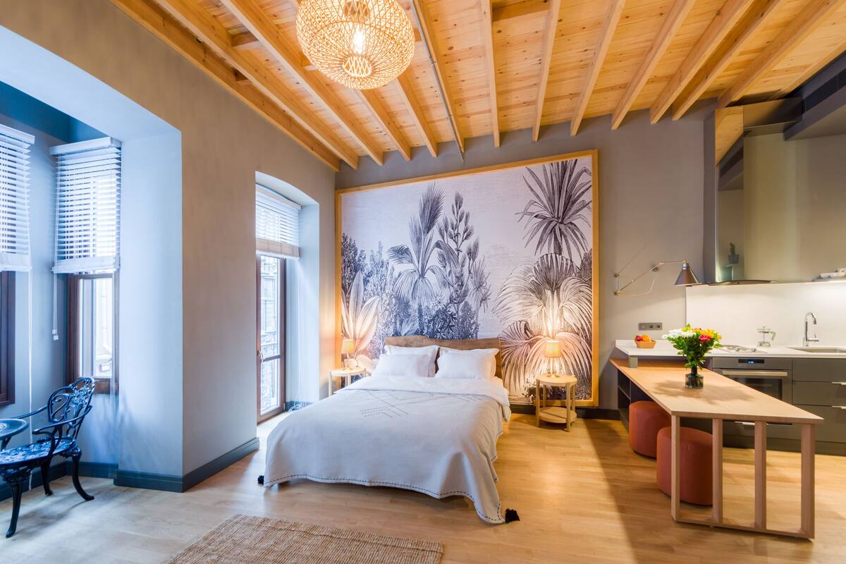 A modern bedroom with a large bed, a desk, and a dining area.
