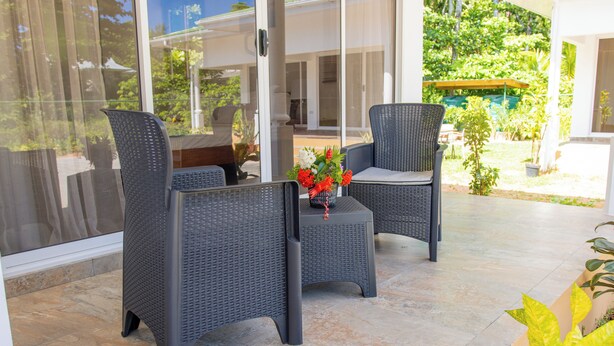 Un patio con mobiliario de mimbre y una pequeña mesa con un jarrón de flores.