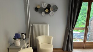 Un salón moderno con un sofá blanco, una mesa de centro con objetos decorativos, un radiador y vistas al exterior a través de un ventanal.
